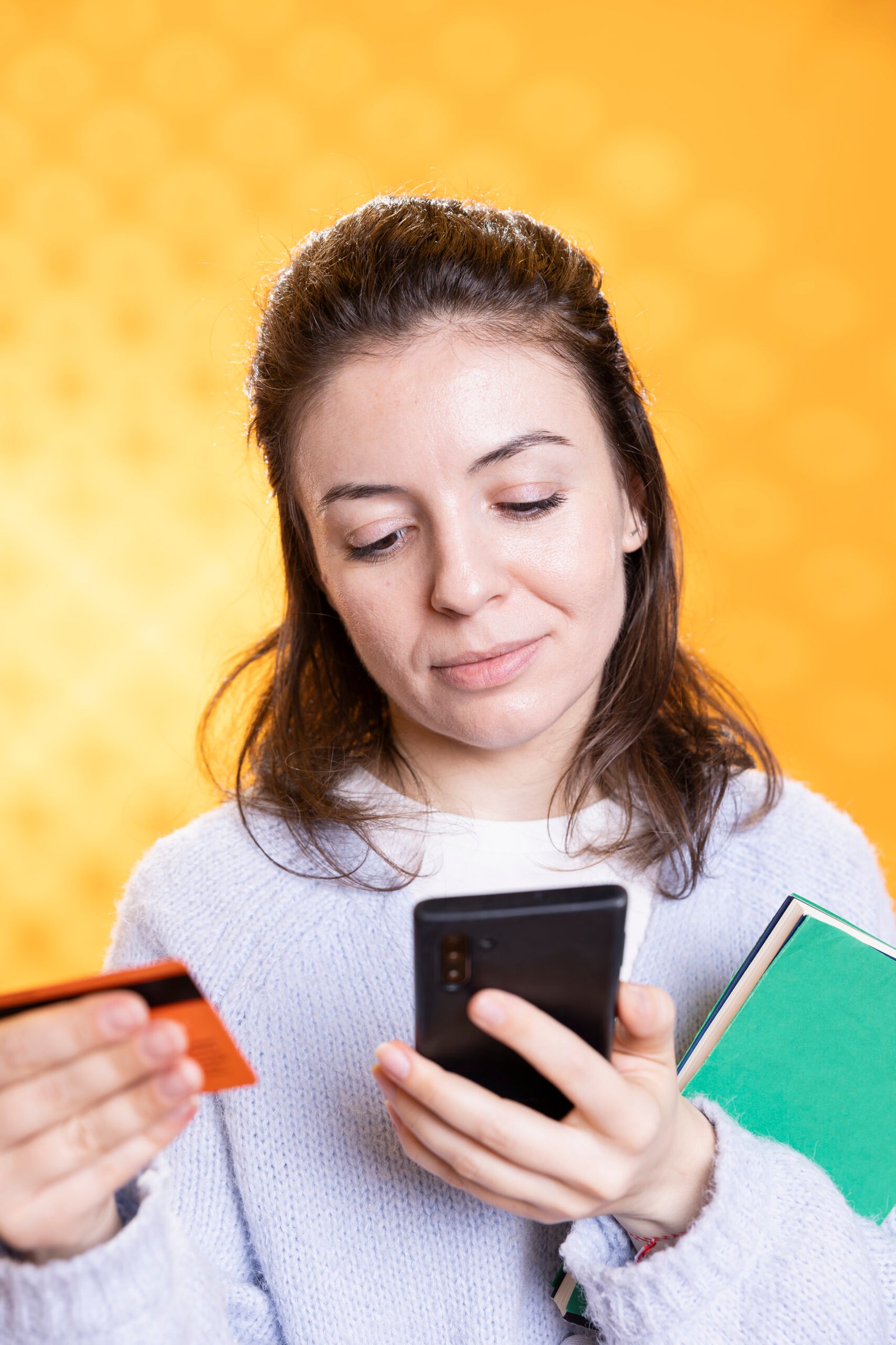 Smiling woman holding books, taking selfies with phone, conveying joy of reading Getbenni.com|Sumter