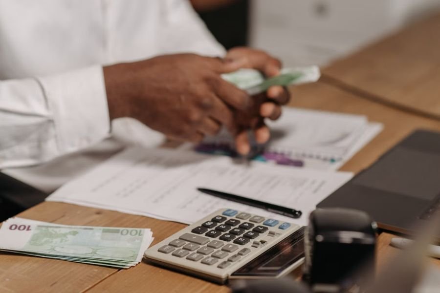 Business professional counting money beside a calculator and financial documents