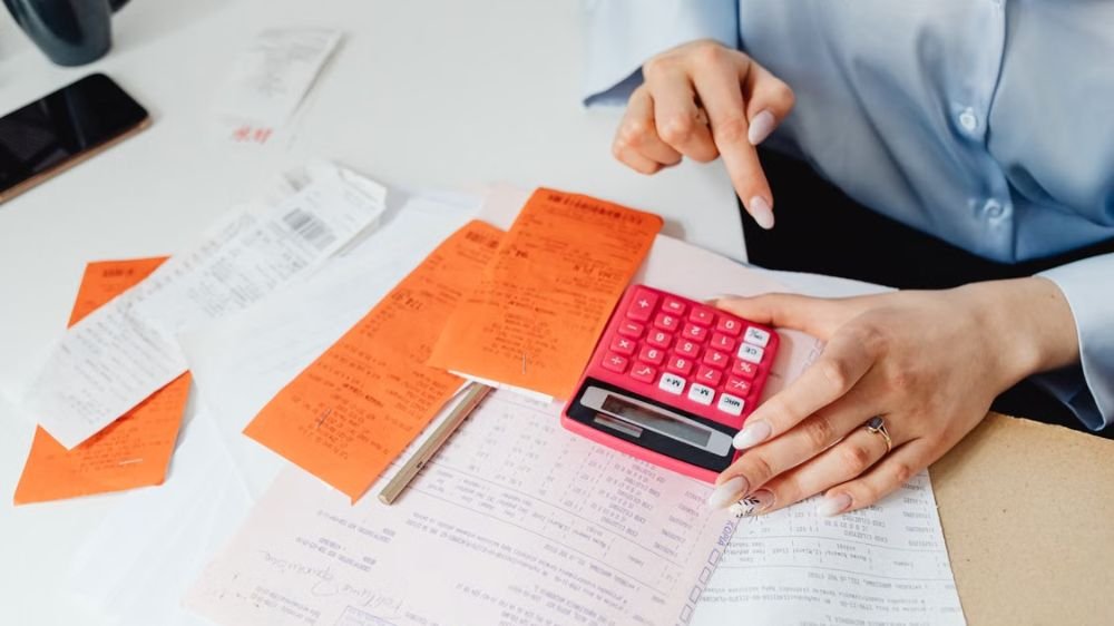 Business owner using a calculator while reviewing financial documents and receipts