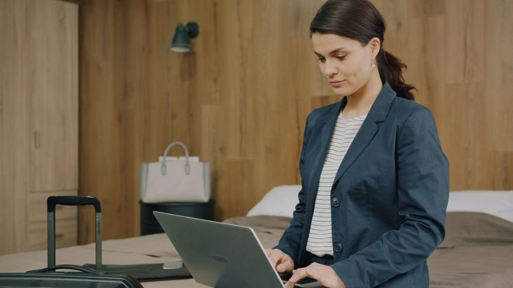 Business traveler using a laptop in a hotel room with luggage nearby
