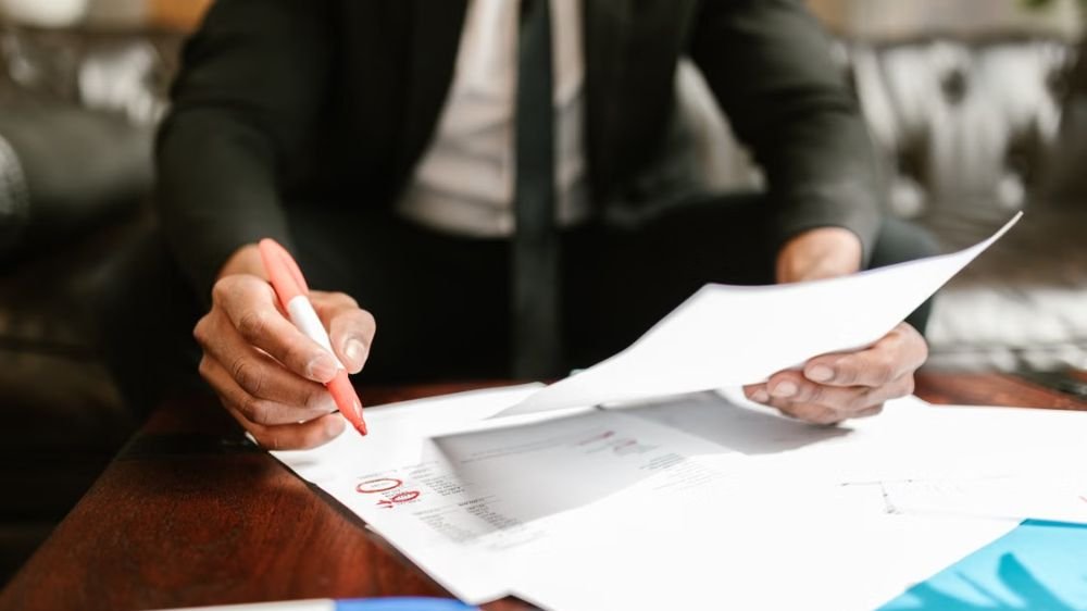 workers-compensation-business-documents Business professional reviewing documents and marking information on paperwork at a desk